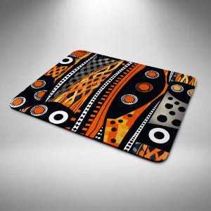 May include: Rectangular mat with a striking abstract design. The mat has a black base with orange, white, and grey geometric patterns. Circles, lines, and diamond shapes create a bold, eye-catching design. Suitable for various uses.