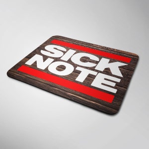 May include: A brown wooden mouse mat with a red stripe and the white text "SICK NOTE" on it.