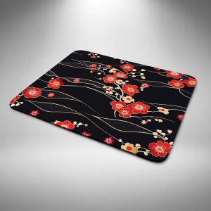 May include: Black rectangular mouse mat with a floral design featuring red blossoms and gold accents. The flowers are arranged on a black background with flowing gold lines. A decorative item for a desk.