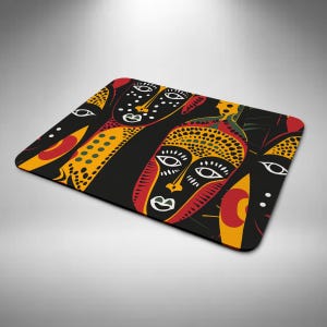 May include: A rectangular black mouse mat with a striking, abstract design of stylized faces. The faces are in red, yellow, and white against a black backdrop, creating a bold artistic statement. The mouse mat is designed for computer use.