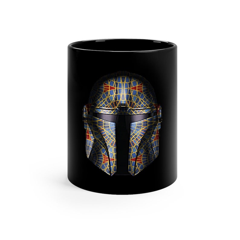 May include: A black ceramic mug with a geometric design of a Mandalorian helmet in blue, yellow, and red.