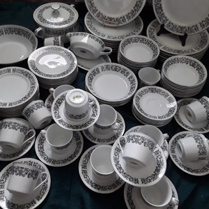 May include: A collection of white ceramic dishes with black floral patterns. The dishes include bowls, plates, and saucers.