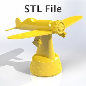 May include: A yellow 3D-printed model of a vintage airplane, mounted on a decorative base. The model features detailed wings, a propeller, and a rounded fuselage. The text "STL File" is displayed above the model.