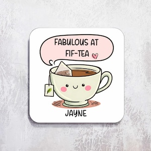 Puede incluir: Posavasos cuadrado blanco con un dise&ntilde;o de taza de t&eacute; de dibujos animados. La taza de t&eacute; est&aacute; llena de t&eacute; y tiene una bolsita de t&eacute;. El texto "FABULOUS AT FIF-TEA" est&aacute; en un bocadillo encima de la taza, con el nombre "JAYNE" debajo.