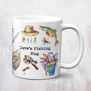 May include: White ceramic mug with a fishing theme. The mug features illustrations of fishing gear, fish, and the text "Dave's Fishing Mug". The design includes a fishing net, a fishing rod, a hat, and a bucket of fish.