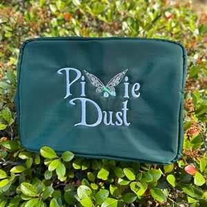 May include: A dark green zippered pouch with the words "Pixie Dust" embroidered in white with a white butterfly design above the text.