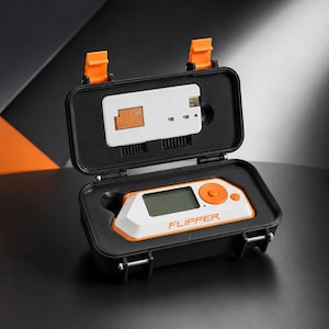 May include: A white and orange Flipper multi-tool device with a digital screen and circular navigation buttons, housed in a black protective carrying case with orange latches. The case lid contains a white rectangular component with copper details.