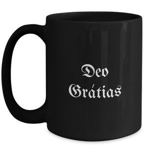 May include: Black ceramic coffee mug with white text that reads "Deo Gratias".