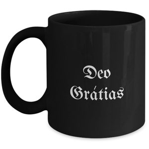 May include: Black ceramic coffee mug with white text that reads "Deo Gratias".
