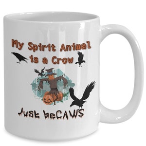 Puede incluir: Taza de caf&eacute; de cer&aacute;mica blanca con una ilustraci&oacute;n en blanco y negro de un espantap&aacute;jaros y cuervos. El texto en la taza dice "My Spirit Animal is a Crow Just Because".