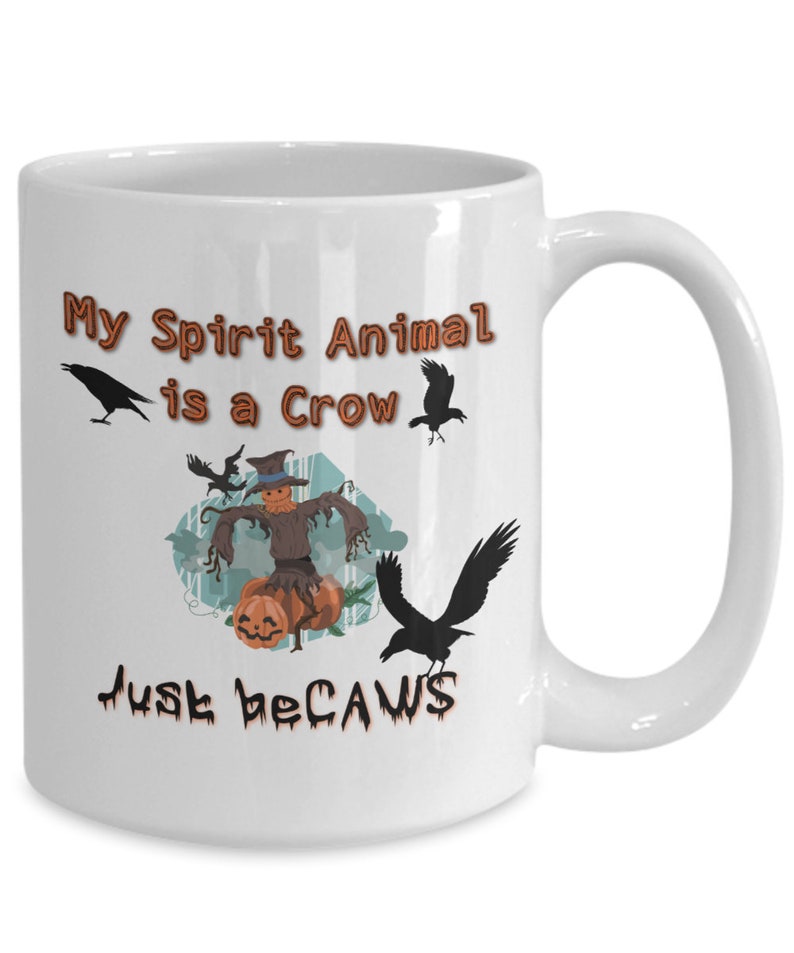 Puede incluir: Taza de caf&eacute; de cer&aacute;mica blanca con una ilustraci&oacute;n en blanco y negro de un espantap&aacute;jaros y cuervos. El texto en la taza dice "My Spirit Animal is a Crow Just Because".