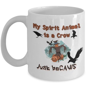 Puede incluir: Taza de caf&eacute; de cer&aacute;mica blanca con una ilustraci&oacute;n en blanco y negro de un cuervo y un espantap&aacute;jaros. El texto en la taza dice "My Spirit Animal is a Crow Just because".
