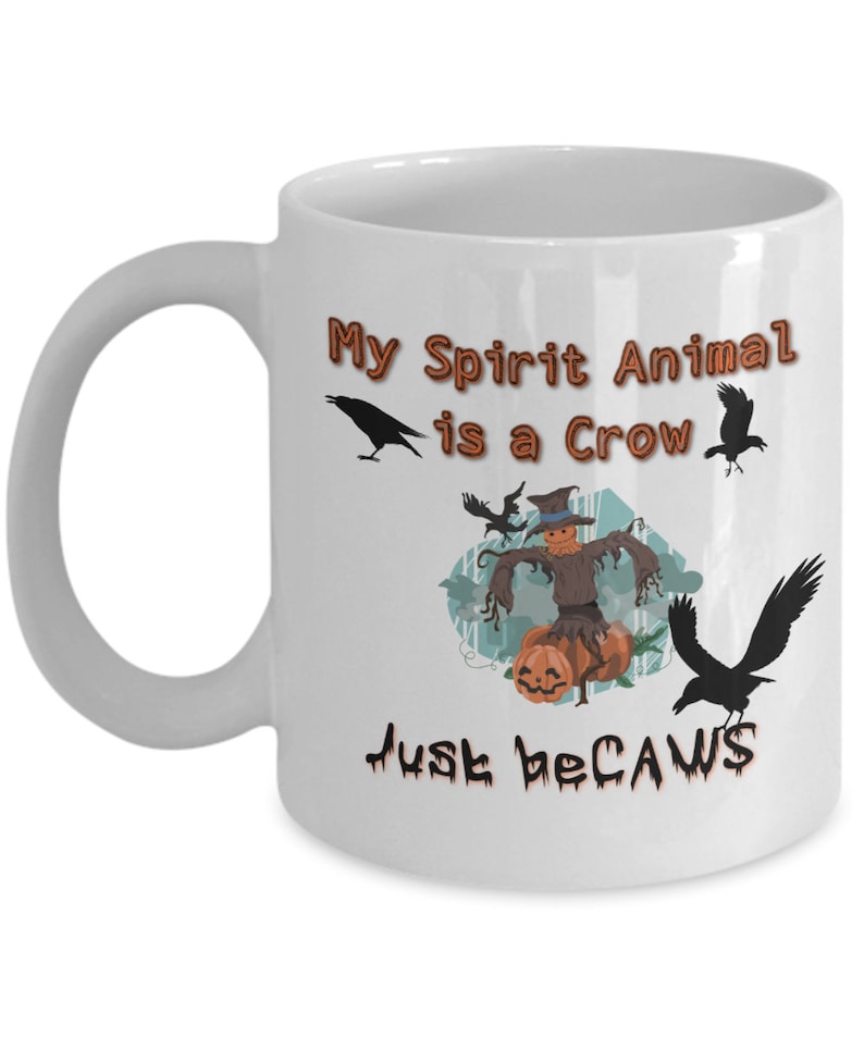 Puede incluir: Taza de caf&eacute; de cer&aacute;mica blanca con una ilustraci&oacute;n en blanco y negro de un cuervo y un espantap&aacute;jaros. El texto en la taza dice "My Spirit Animal is a Crow Just because".
