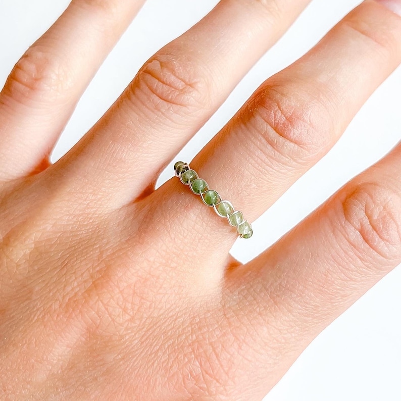 May include: A silver wire wrapped ring with green gemstone beads.