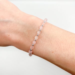 May include: A delicate bracelet made with pale pink rose quartz beads and silver spacer beads.