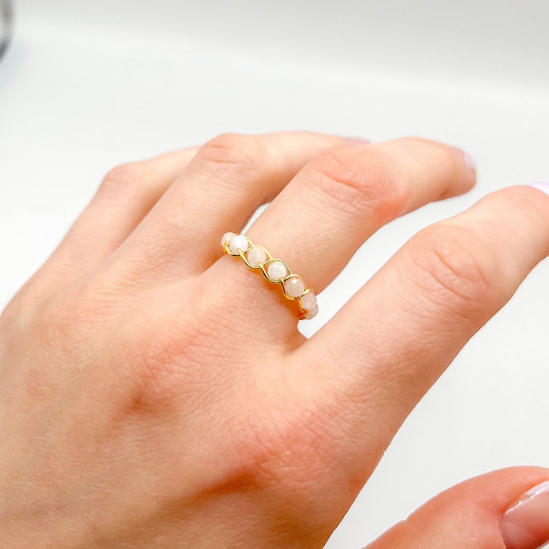 Puede incluir: Un anillo de oro con cuentas blancas. El anillo est&aacute; en el dedo de una persona.
