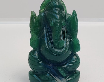 Puede incluir: Una pequeña figura de piedra verde oscuro translúcida tallada con la forma de la deidad Ganesha. La figura está representada en posición sentada con cabeza de elefante, trompa y orejas grandes, con superficies lisas y pulidas.