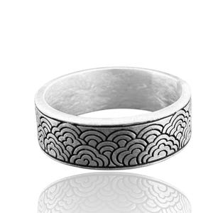 May include: A silver ring with a detailed wave pattern around the band. The ring has a matte finish and a wide band design. The wave pattern is a repeating design of curved lines, creating a textured look. The ring is displayed on a white background.