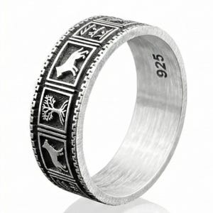Peut inclure: Une bague en argent avec un motif répétitif de petits panneaux carrés. Chaque panneau présente un motif gravé différent, notamment une main, un arbre et un animal en course. La bague est marquée "925" à l'intérieur.