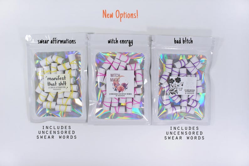 May include: Three white holographic pouches containing small white paper scrolls tied with colored rubber bands. The labels read swear affirmations, manifest that shit, witch energy, witch magic, bad b!tch, and includes uncensored swear words.