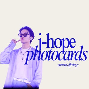 May include: Image features the text "j-hope photocards" in a stylized blue font, with "current offerings" below. A person wearing sunglasses and a light purple outfit is in the image. The background is a light beige color.