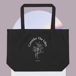 May include: Black tote bag with white text and a floral design. The text reads "Consider The Lilies" with "Luke 12:27" below the design.