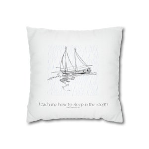 Könnte beinhalten: Ein weißes Kissen mit einer Schwarzweißillustration eines Segelboots in einem Regensturm. Der Text "teach me how to sleep in the storm" ist unter dem Bild gedruckt, mit dem Schriftzitat "Matthew 8:23-27" in kleinerer Schrift darunter.