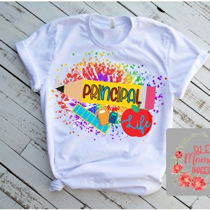 Peut inclure: T-shirt blanc avec un motif de peinture &eacute;clabouss&eacute; color&eacute;. Le motif comprend un crayon, une r&egrave;gle, un cahier, une calculatrice et une pomme avec le texte "Principal Life".