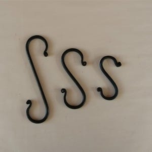 May include: Three black metal S-shaped hooks of varying sizes.
