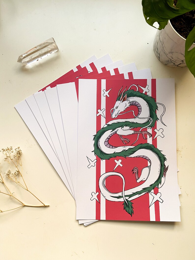 May include: A stack of white cards with a red background featuring a white and green dragon with white crosses on the red background.