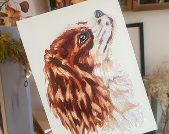 Può includere: Dipinto di un Cavalier King Charles Spaniel che guarda in alto. Il pelo del cane è un mix di marrone e bianco, con pennellate dettagliate. L'opera d'arte è tenuta da una persona.