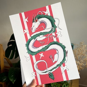 May include: A white and green dragon illustration with a pink background. The dragon is curled up in a circle with its head facing the left. The background has white crosses on it.