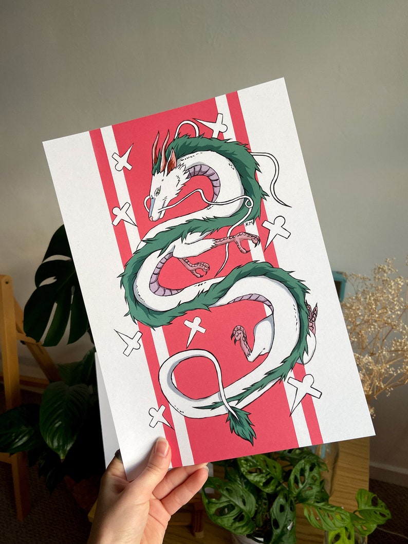 May include: A white and green dragon illustration with a pink background. The dragon is curled up in a circle with its head facing the left. The background has white crosses on it.