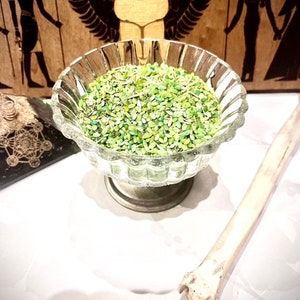 Peut inclure: Un bol en verre rempli d'herbes séchées vertes et blanches. Le bol est posé sur une surface blanche.