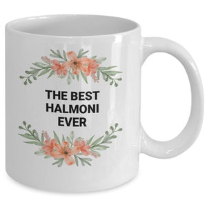 May include: White ceramic coffee mug with a floral design and the text "THE BEST HALMONI EVER" in black.