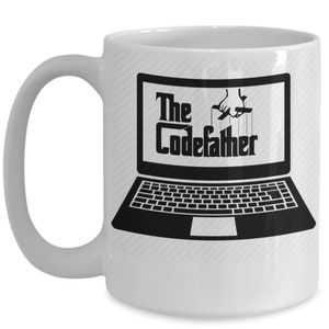 May include: White ceramic coffee mug featuring a black and white image of a laptop with the text "The CodeFather" displayed on the screen. The laptop is set against a white background with a subtle striped pattern.