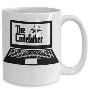 May include: White ceramic mug featuring a black and white image of a laptop with the text "The CodeFather" on the screen. A hand is depicted controlling the laptop with strings.