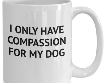 May include: White ceramic coffee mug with black text that reads "I only have compassion for my dog".