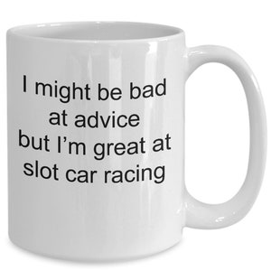 May include: White ceramic coffee mug with black text that reads "I might be bad at advice but I'm great at slot car racing."