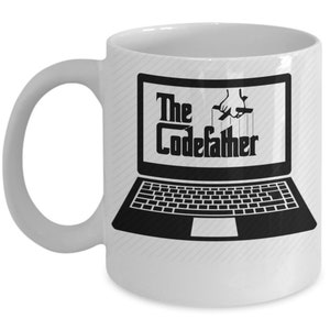May include: White ceramic coffee mug featuring a black and white image of a laptop with the text "The CodeFather" on the screen. The laptop is being controlled by a hand with strings.