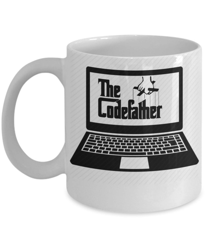 May include: White ceramic coffee mug featuring a black and white image of a laptop with the text "The CodeFather" on the screen. The laptop is being controlled by a hand with strings.