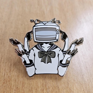 May include: A silver enamel pin depicting a cartoon character with a television for a head, wearing a white sailor uniform with a black bow tie. The character has four arms, each with a different hand gesture.