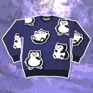 Può includere: Un maglione blu navy con diverse toppe di personaggi dei cartoni animati bianchi e neri. Il maglione ha un girocollo, maniche lunghe e polsini e orlo a coste. Le toppe sono di varie dimensioni e pose, aggiungendo un tocco giocoso all'indumento.