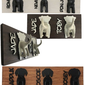 K&ouml;nnte beinhalten: Hakenleiste aus Holz mit drei schwarzen Haken in Form von Hundepopos und den Namen "Romeo", "Nevaeh" und "Don Julio", die vertikal auf der Leiste geschrieben sind.