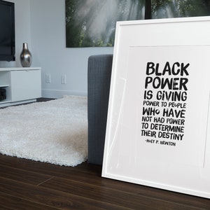 May include: A framed black and white print with the quote "Black Power is giving power to people who have not had power to determine their destiny - Huey P. Newton".