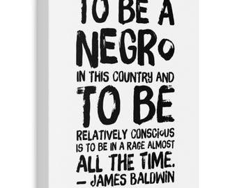 May include: White canvas art print with black text. The quote reads: "TO BE A NEGRO IN THIS COUNTRY AND TO BE RELATIVELY CONSCIOUS IS TO BE IN A RAGE ALMOST ALL THE TIME. - JAMES BALDWIN."