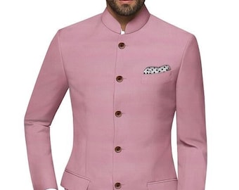 Pode incluir: Um blazer rosa com gola mandarim e fecho de um único botão. O blazer tem um bolso no lado esquerdo e é combinado com calças azul-escuras e sapatos marrons.