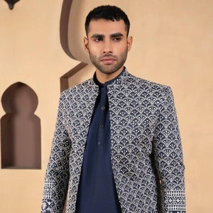 May include: A navy blue long-sleeved jacket with a white geometric pattern. The jacket has a mandarin collar and a button closure.