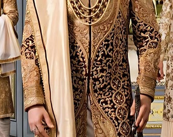 May include: A man wearing a traditional Indian wedding outfit. The outfit is a maroon and gold sherwani with intricate embroidery. He is also wearing a white turban and a gold necklace.