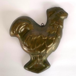 May include: A vintage bronze-colored rooster-shaped mold. The mold features detailed feather and comb textures, with a small loop for hanging. The rooster stands on a diamond-shaped base, showcasing a classic kitchenware design.